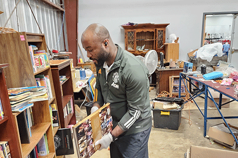 Pharmacy student Valentine Orock stacks books at his local Salvation Army.