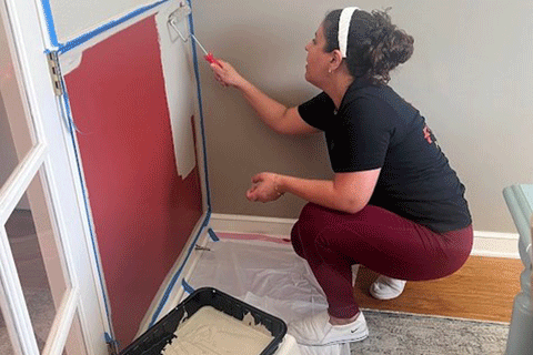 A pharmacy student helps paint a wall at a local organization.