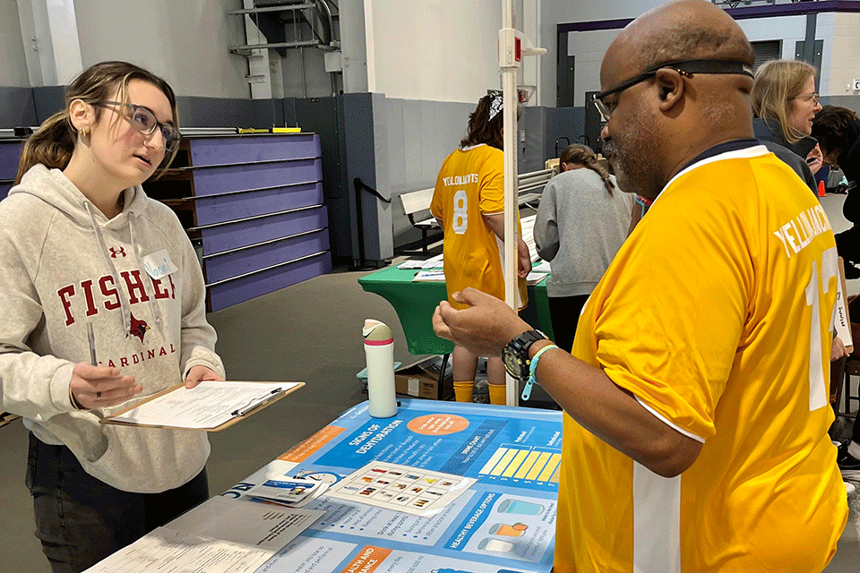 A Fisher nursing student shares information about the importance of hydration with an attendee of the competition.