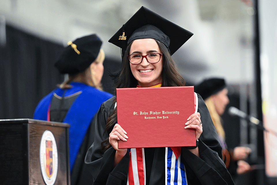 A member of the Class of 2024 proudly holds up their diploma.