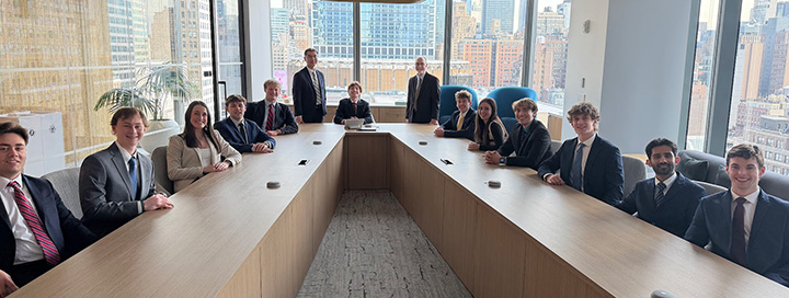 Members of the Investment Club sit together in a board room in New York City.