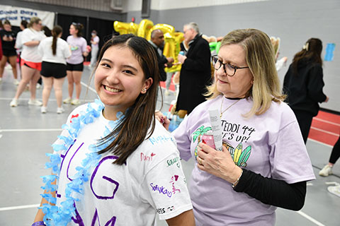 A smiling student with a woman signing the back of her t-shirt at the Teddi Dance