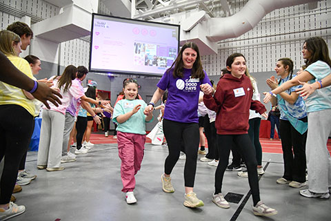 A camp volunteer holding hands with two campers running through the student tunnel