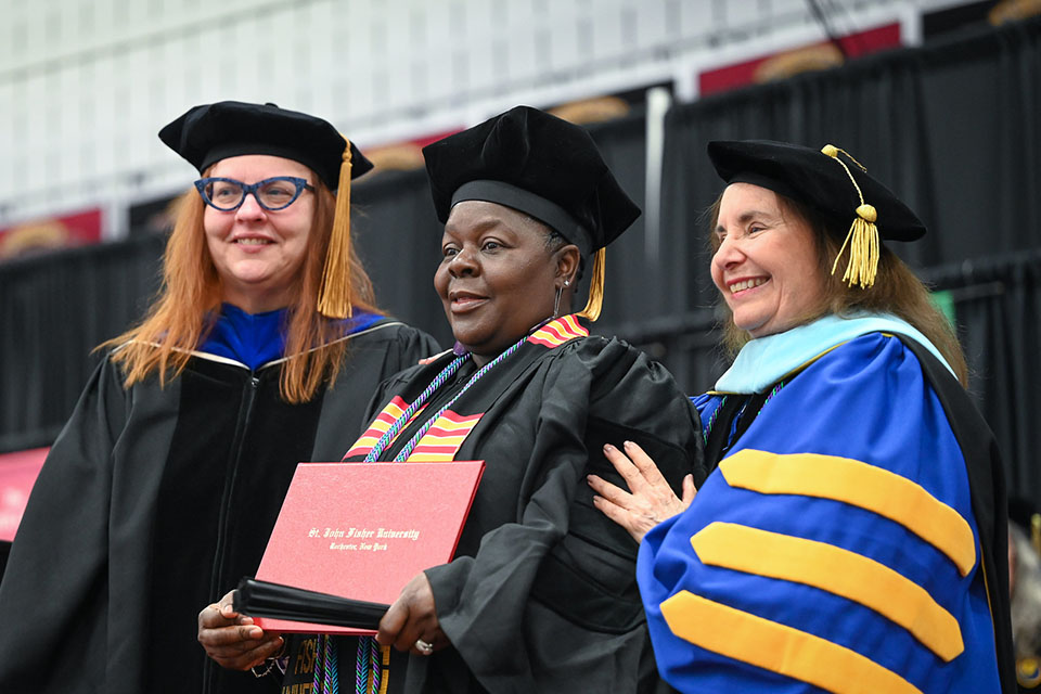 A student receiving her doctoral hood and diploma at Commencement