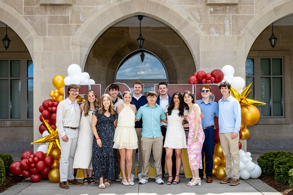 A group of male and female students in front of a Fisher Alumni sign