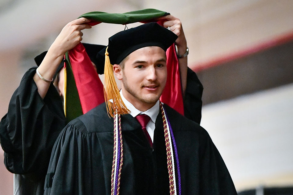 Alexander Cain receiving his Doctor of Pharmacy hood.