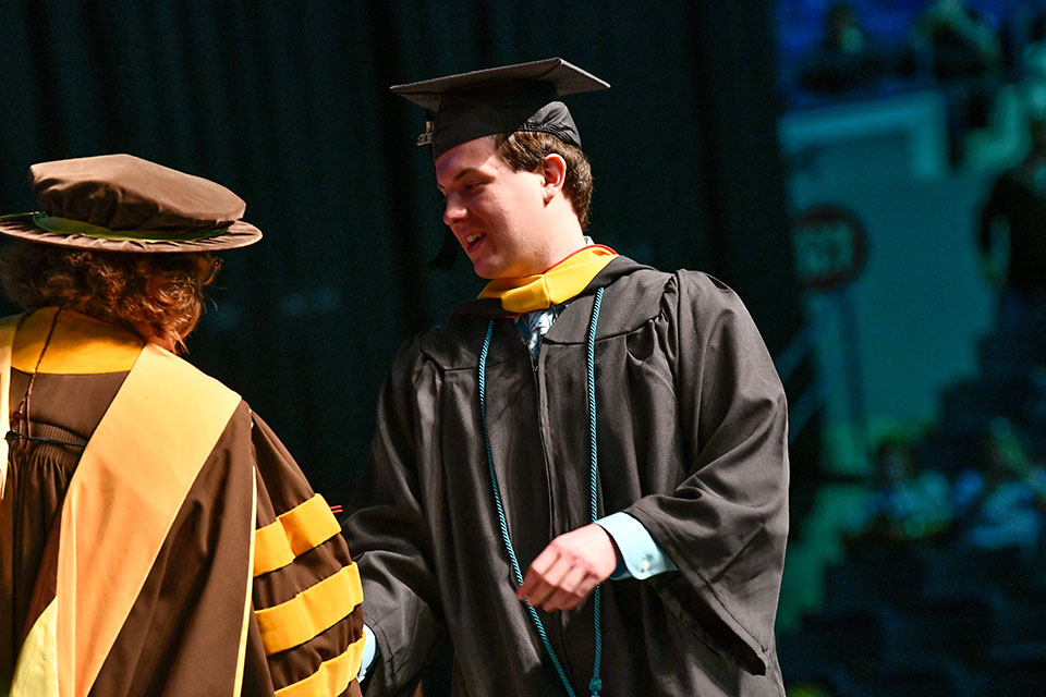 Sport management graduate Evan Siebert shakes a dean's hand during Commencement.