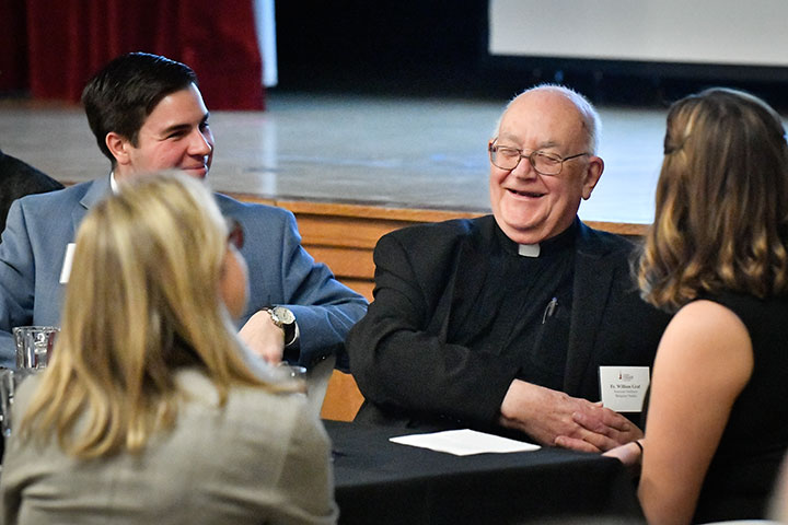 Fr. Graf talks with students at the 2019 Scholarship Dinner.