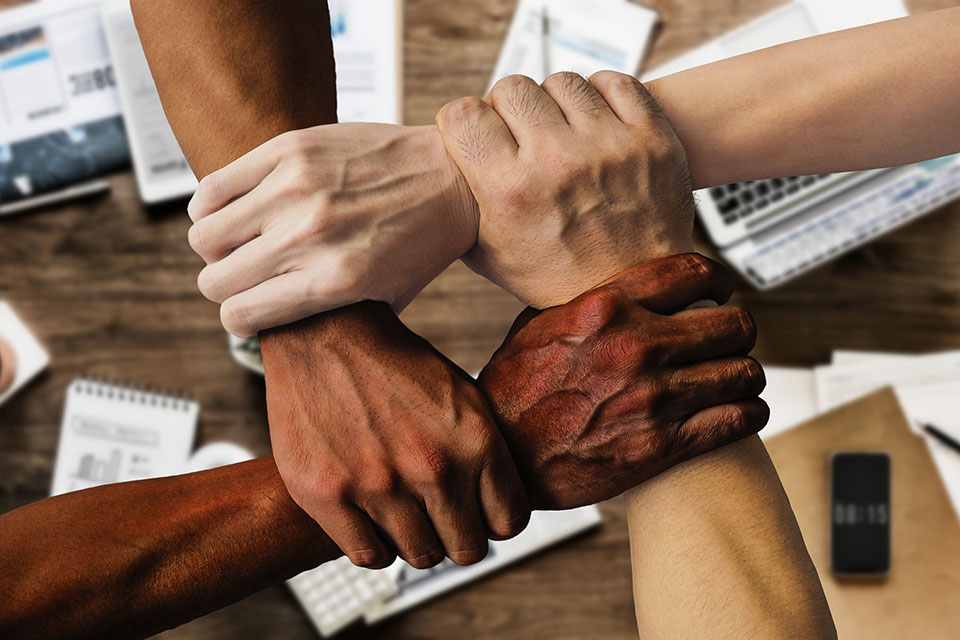 A diverse group of people clasp hands.