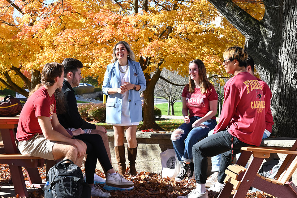 On a sunny day, a professor delivers a lecture to students on the patio at LeChase Commons.