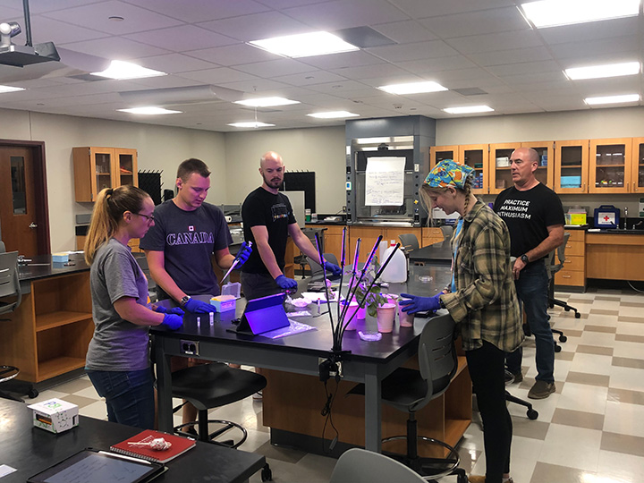 A group participates in a hands-on project in a biology lab as part of Fisher's AP Summer Institute.