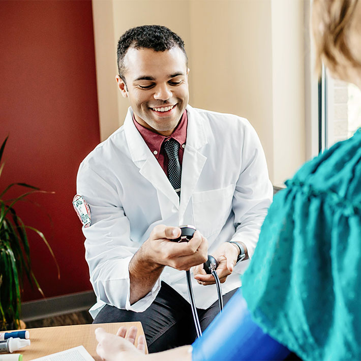 A pharmacy student takes a patient's blood pressure.