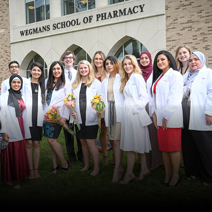 Recent graduates stand outside the Wegmans School of Pharmacy.
