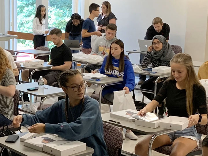 Students unbox iPads in a classroom.