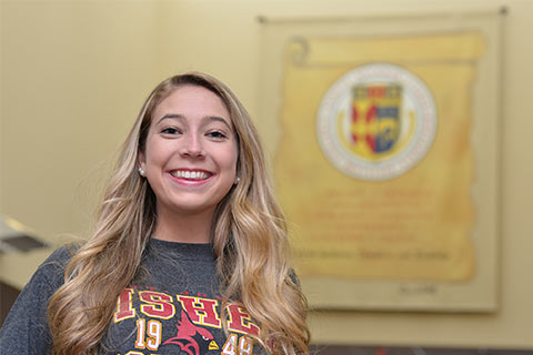 Student standing in front of Fisher Creed