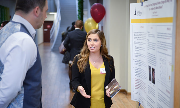 Student Explaining Poster at Research Symposium