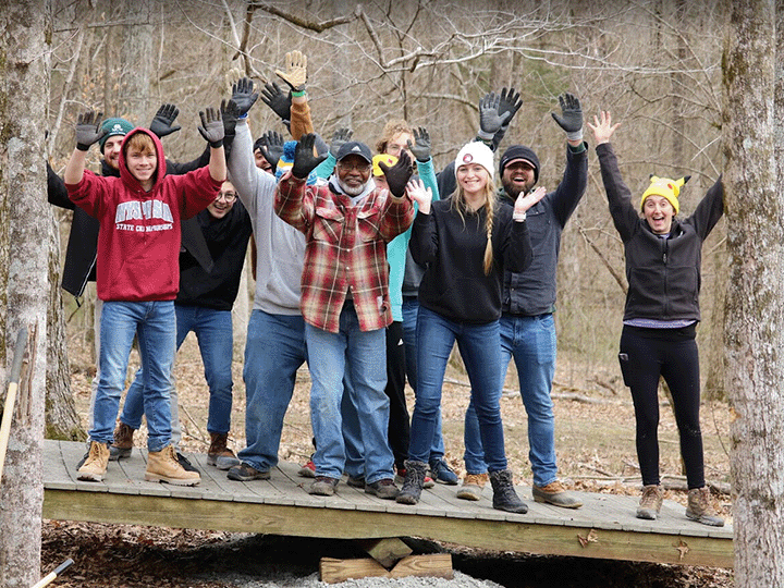 Students standing on a balance board during community service.