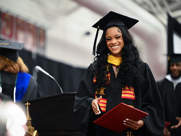 A student in commencement regalia receives her diploma.