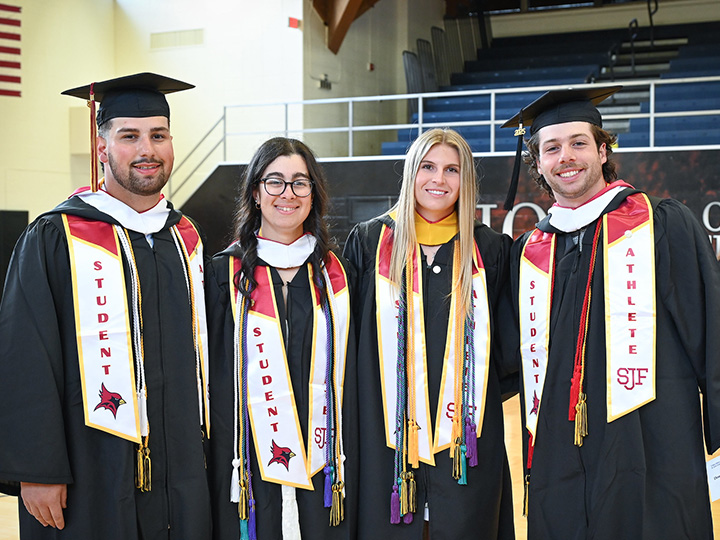 Students athletes stand together in Commencement regalia.