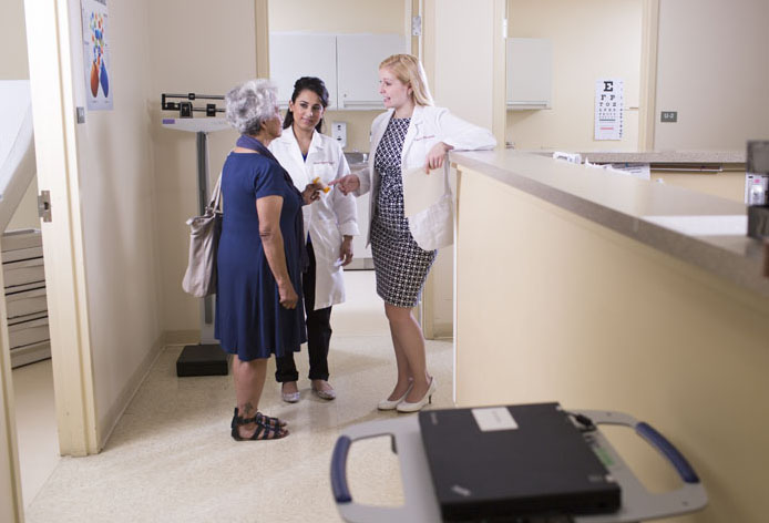 Two pharmacists consult with a patient in a hospital setting.