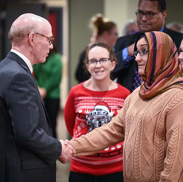 Fisher President Dr. Rooney shakes hands with Associate Professor Dr. Ahmed.