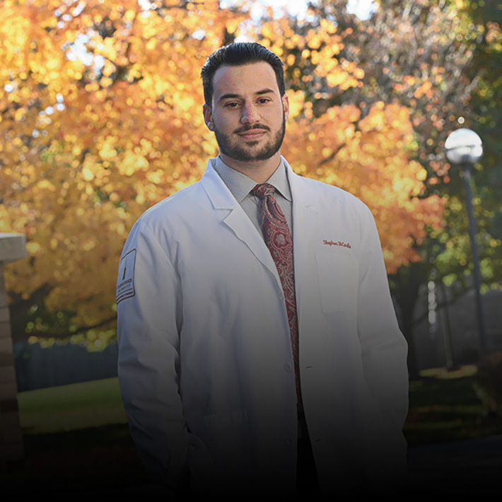 A pharmacist stands on campus at St. John Fisher University.