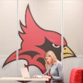 A Fisher student works at a laptop in front of Cardinal mascot.