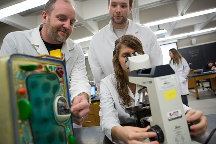 Professor Boller with students looking in microscope