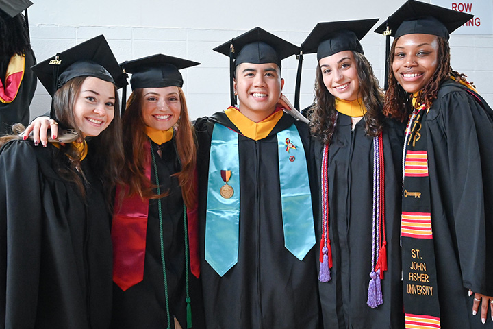 Students stand together in commencement regalia.