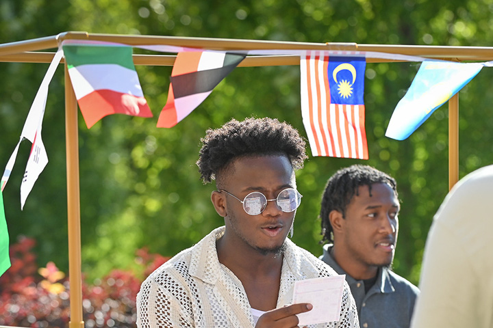 A student visits a booth with flags representing multiple countries at the Inclusion Dinner event at Fisher.