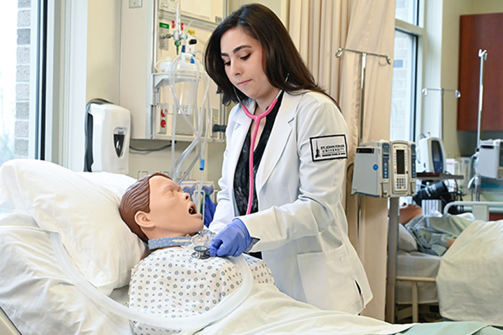 A nursing student uses a stethoscope in a simulation center.