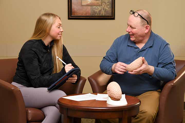 A student working with a professor looking at a model of the brain.