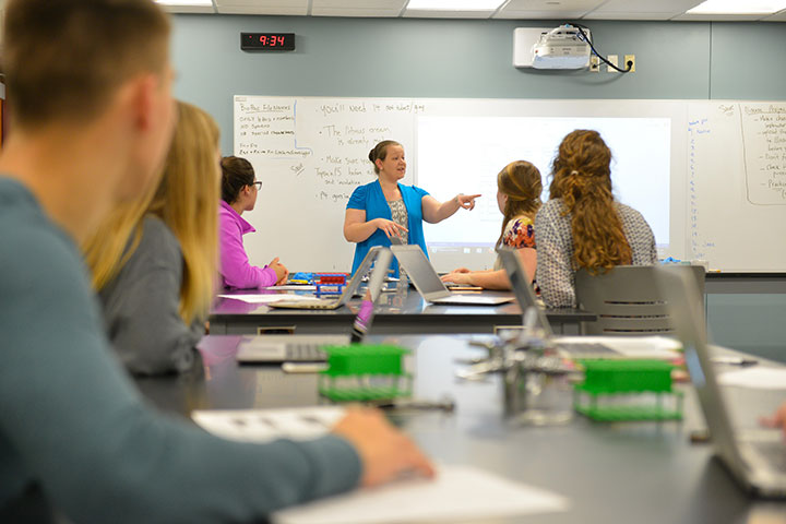 Faculty member pointing at front of science classroom.
