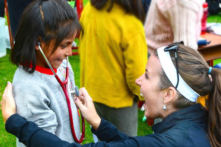 A nursing student allows a child to hear her own heartbeat through a stethoscope.