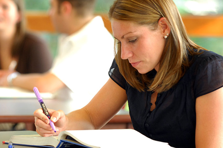 Student studying textbook with highlighter in hand