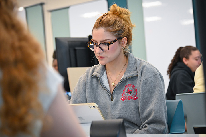 A student works on an iPad in a classroom.