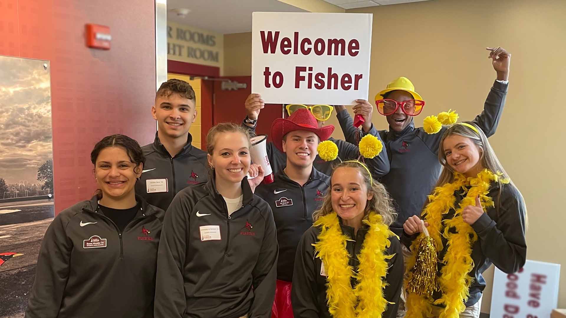 A group of people with Fisher gear holds a sign that says Welcome to Fisher.