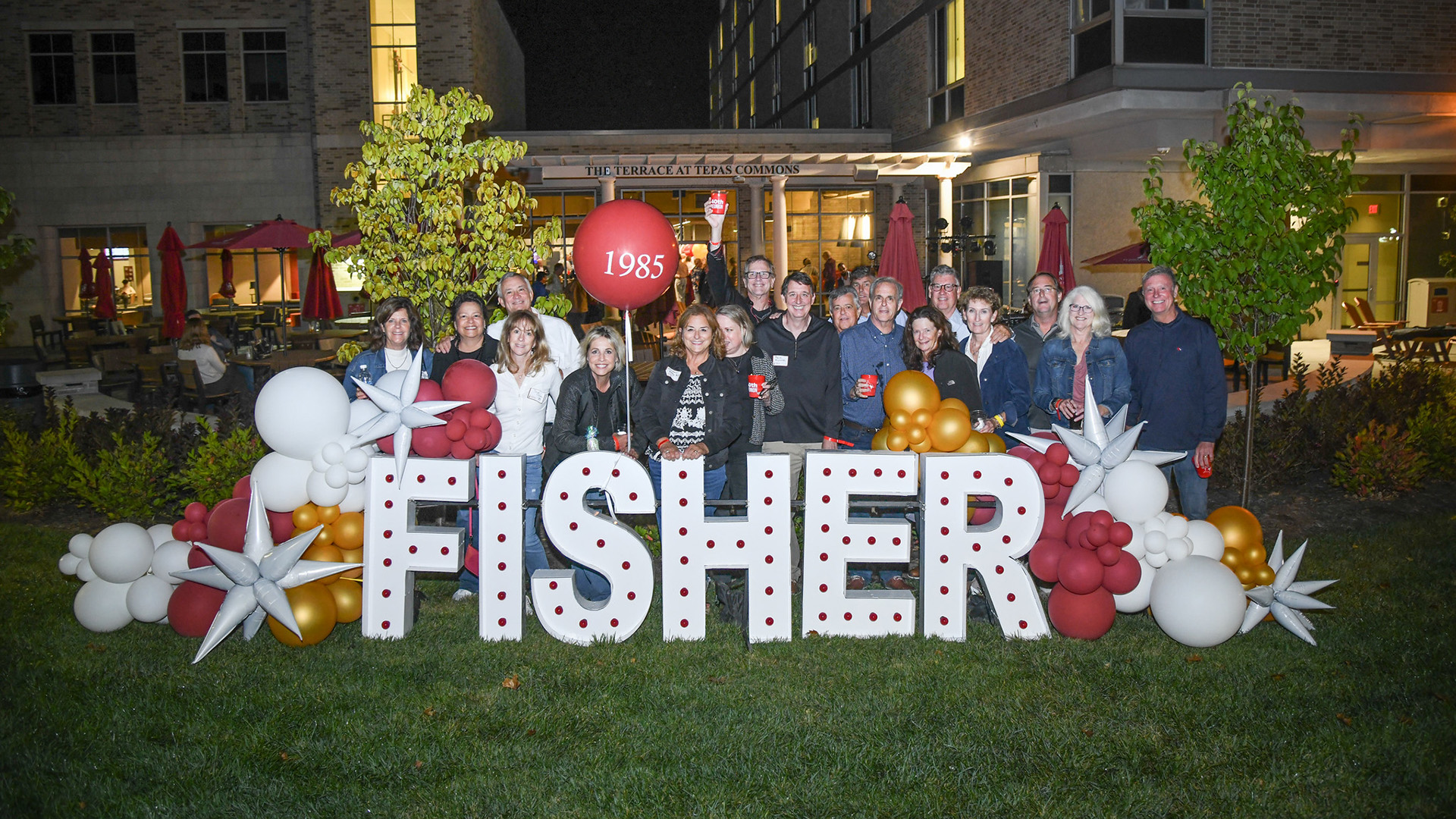 Alumni standing with the Fisher sign.