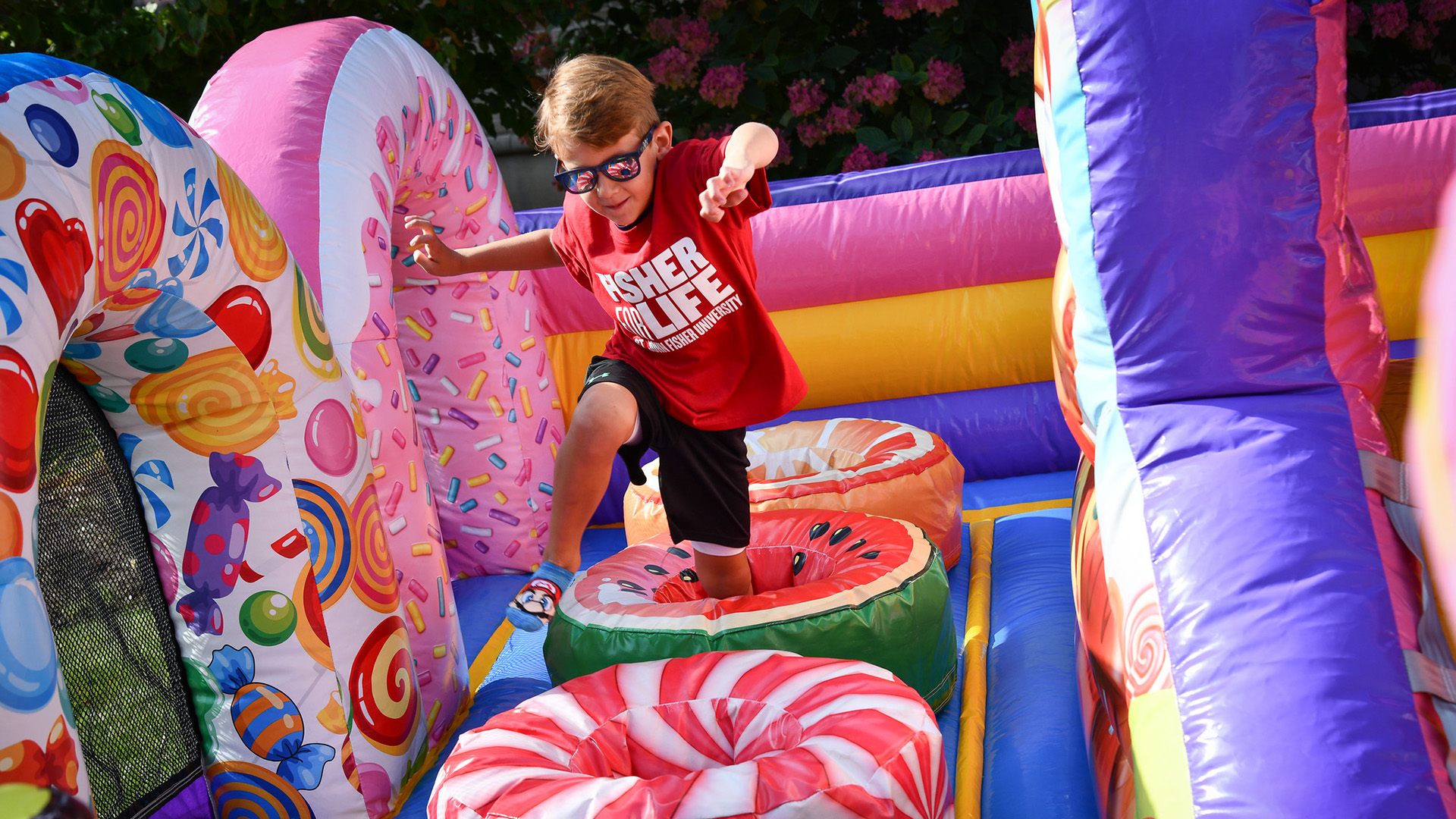 A kid wearing a Fisher For Life shirt plays in a bounce house during Alumni Weekend at St. John Fisher University.