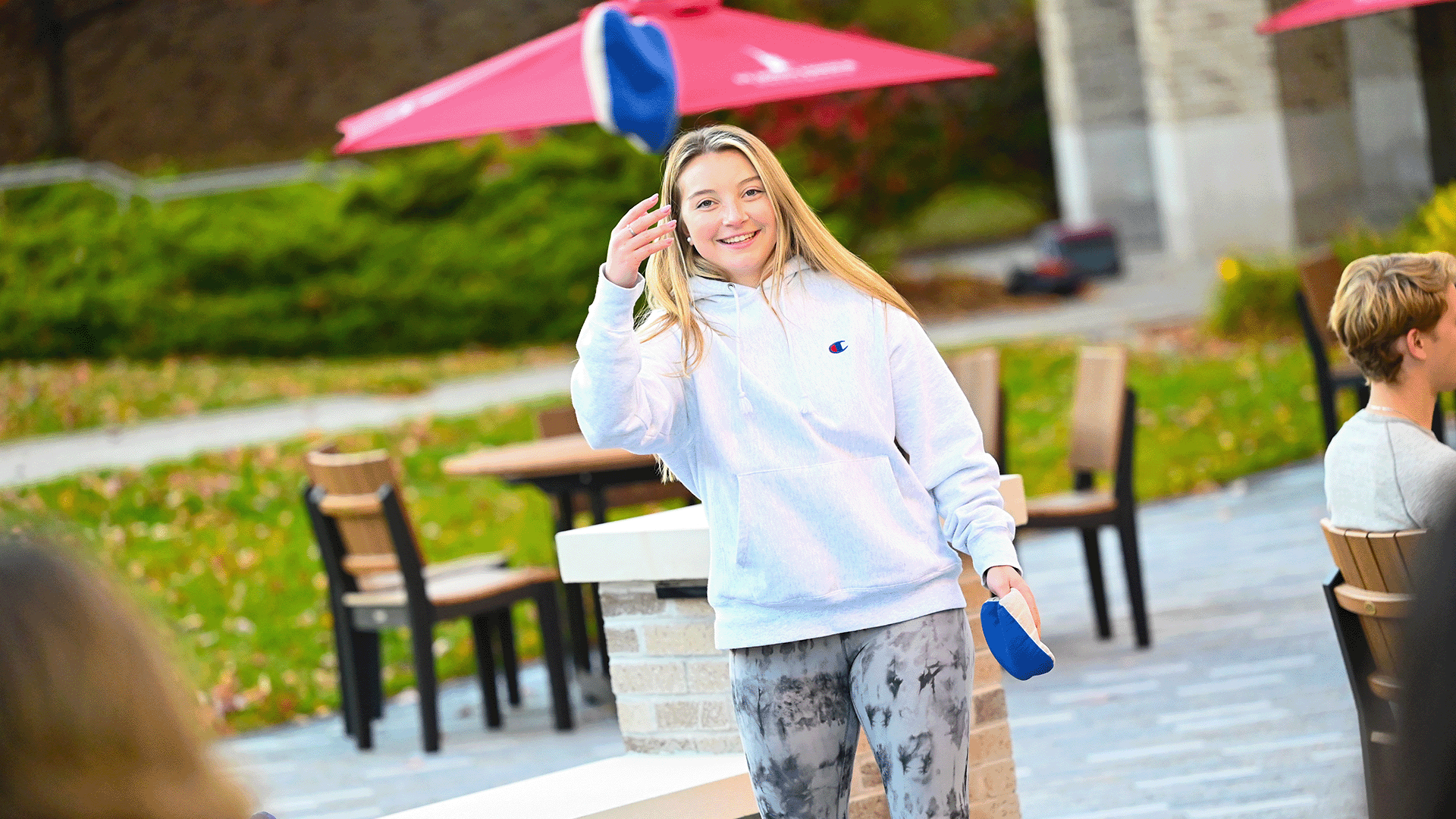 A student tosses a bean bag while playing a lawn game on campus.