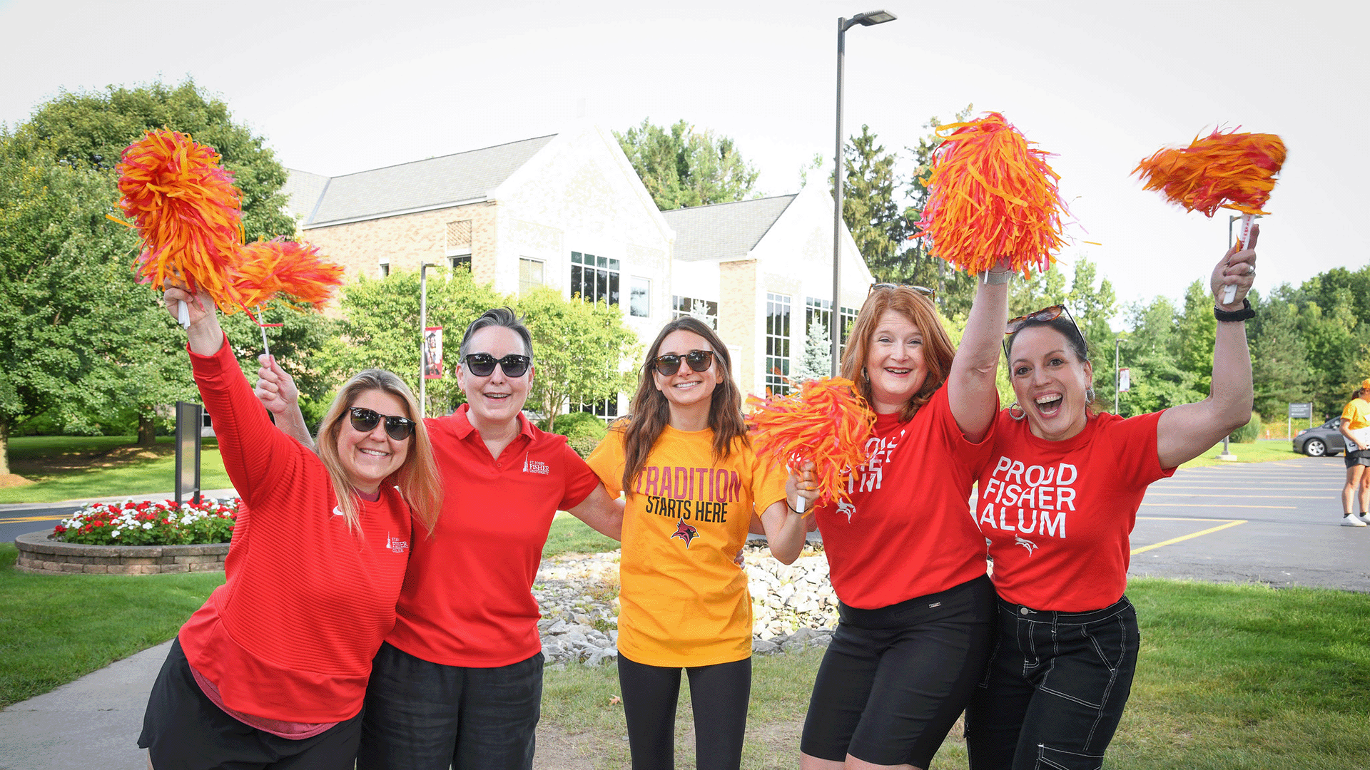 A group of staff and alumni wave pompoms in celebration.