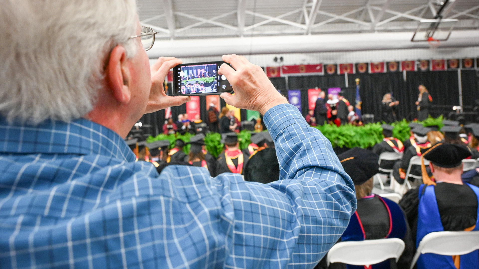 A Commencement attendee takes photos during the ceremony.
