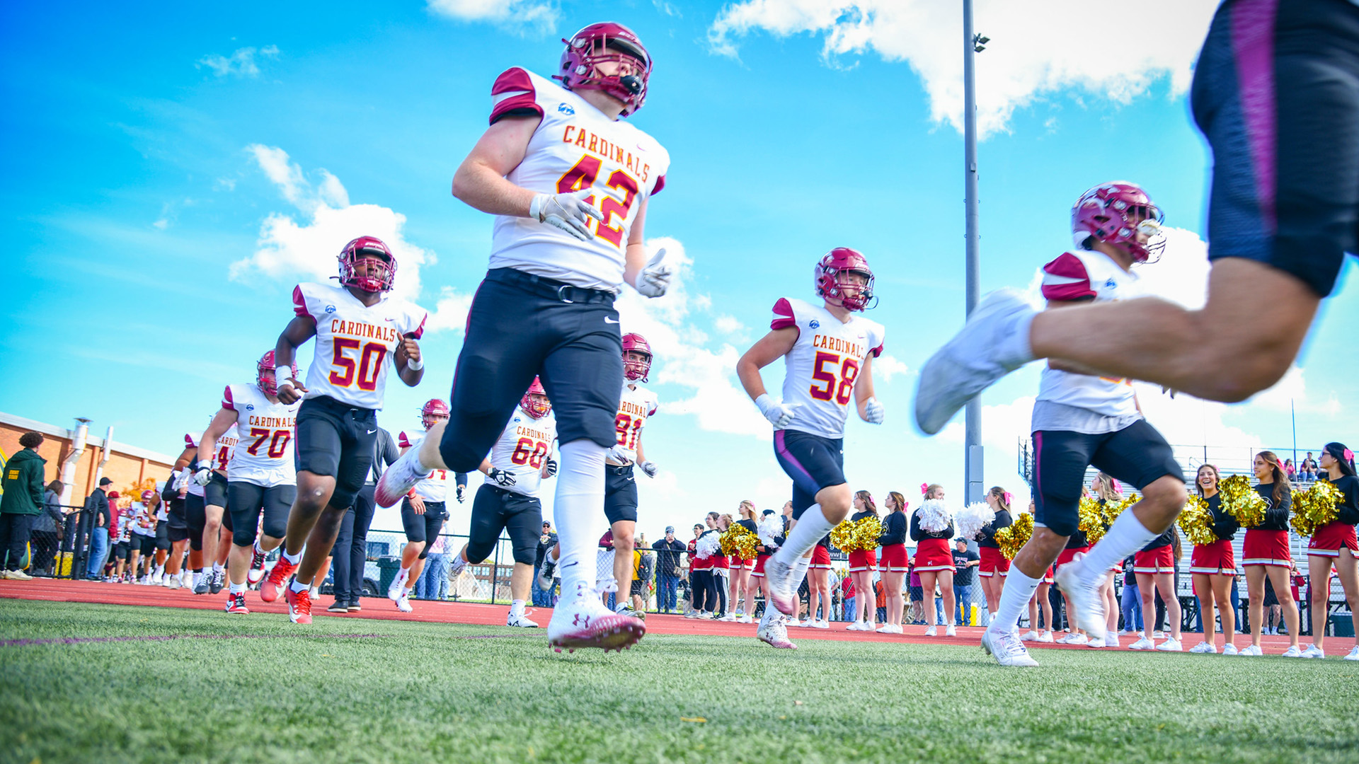 Football players run on the field for the Courage Bowl for Camp Good Days and Special Times.