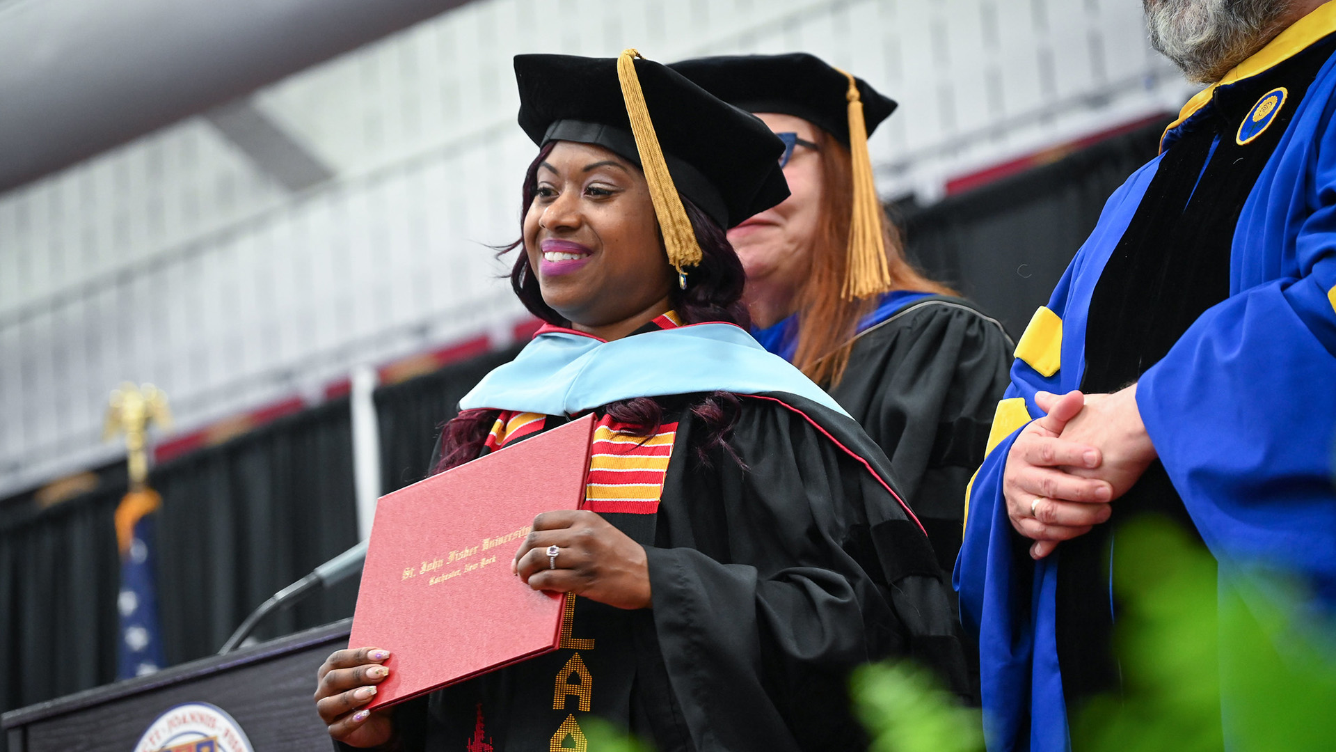 An Ed.D. graduate holds her diploma after hooding at commencement.