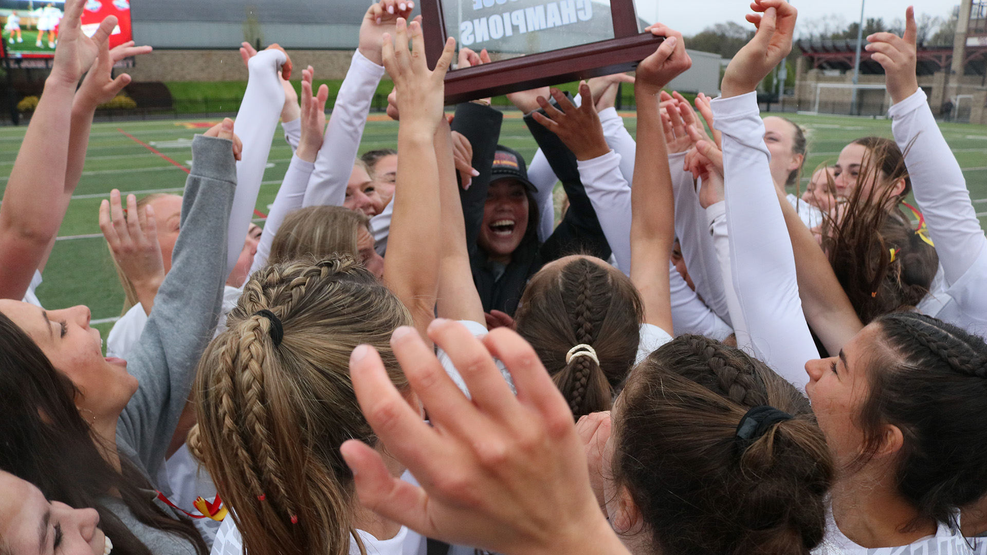 Fisher athletes celebrate together raising a championship plaque as a team.