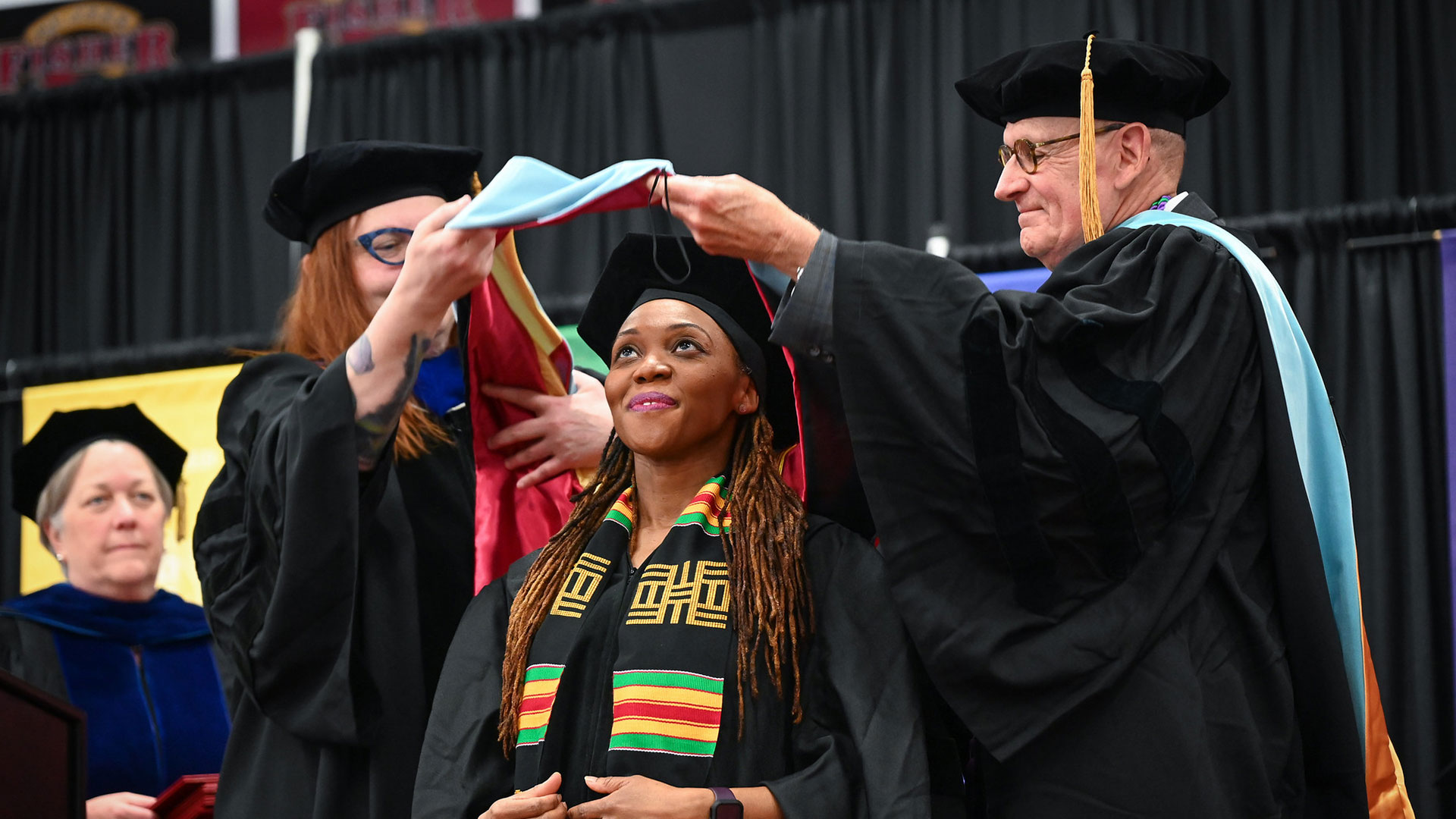A student is hooded at commencement.