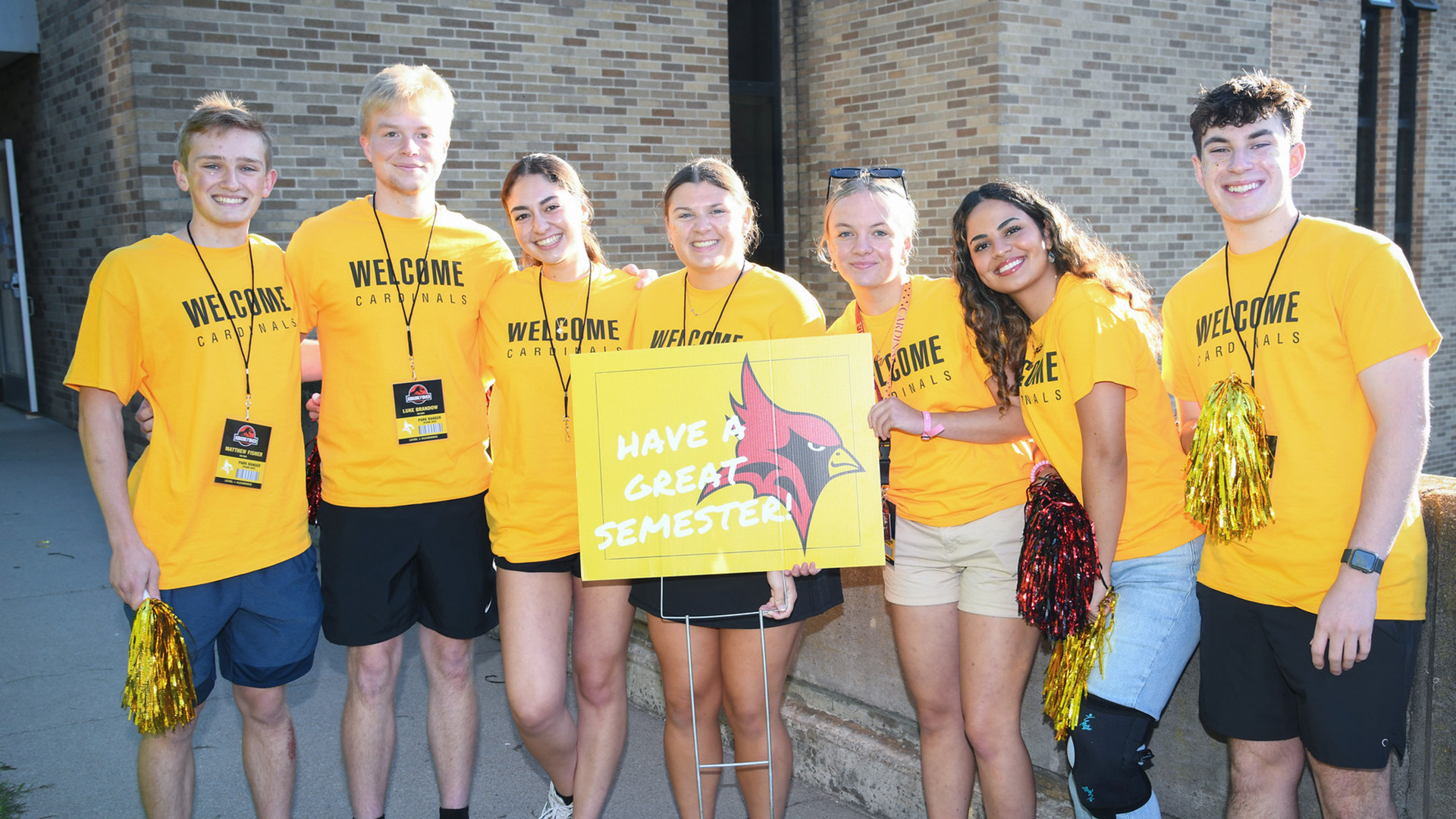 A group of students welcome incoming students to Fisher with welcome signs.