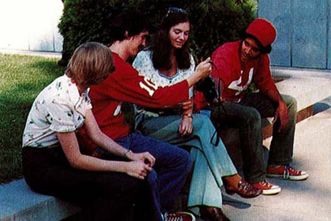 Four students seated outside chatting in 1975