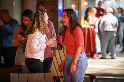Two alumni laughing at an outdoor event