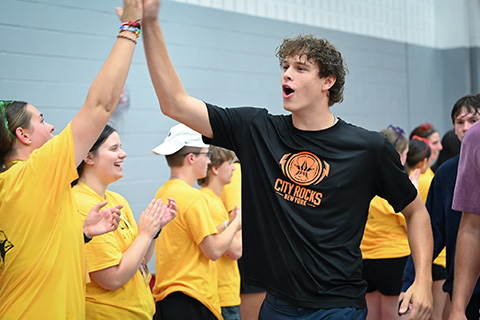 Cardinal welcomes students with a high-five during Welcome Weekend.